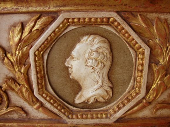 A stately Swedish Gustav III ivory painted and parcel gilt rectangular mirror; the rectangular split mercury plate within a carved wooden frame; surmounted by a frieze centering a terracotta profile flanked by carved foliate and floral embellishments
