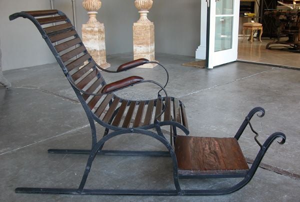 A charming Swedish folk art wooden and iron child's sled; the slatted wooden chair over a wooden foot rest; applied to an iron frame over iron runners