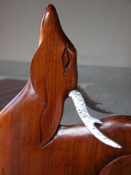 A graceful French art deco carved bubinga wood deer; the slim stylized deer with dramatic upturned head; standing on 2 elongated slender legs; raised on a domed aluminum base