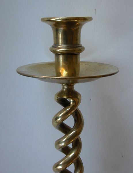 A boldly-scaled pair of English Victorian barley twist brass candlesticks; each tall stick with deep candlecup resting on a wide drip pan; above a spiraling barley twist support all over a circular cup-shaped base