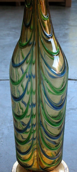A stylish pair of Italian mid-century honey-colored glass bottle-form lamps with raised blue and green swags; each hand-blown tall bottle-form vessel of honey colored glass adorned with dripping blue and green swags; all resting on a gilt metal