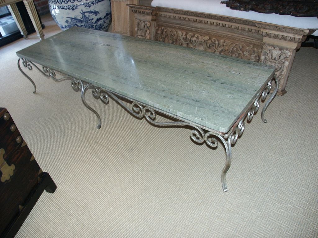 Great looking long coffee table that would also lend itself to  being used as a bench or banquette with great looking scrolling silvered iron and unusual marble top slab.
