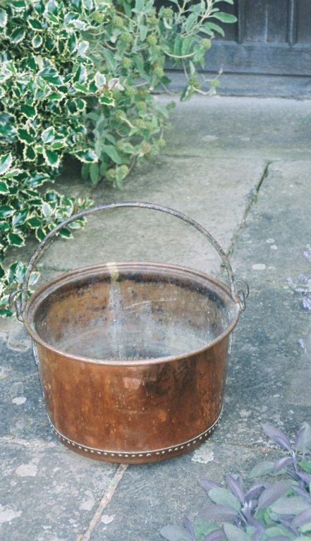 An 18th century English hand rivetted copper apple kettle with wrought iron carrying handle having decorative iron hinges