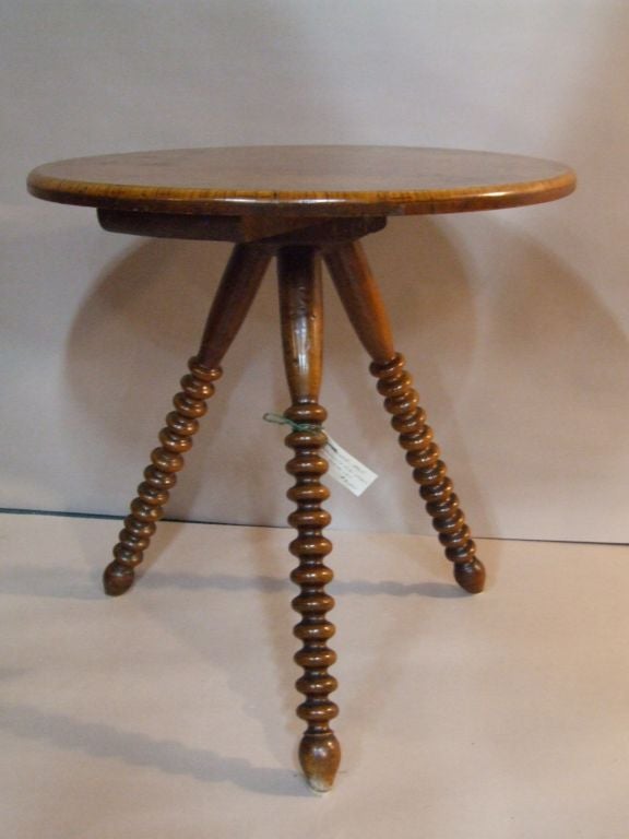 A visually interesting round walnut burlwood gypsy table with banded top on boldly turned bobbin legs ending in tulip feet.