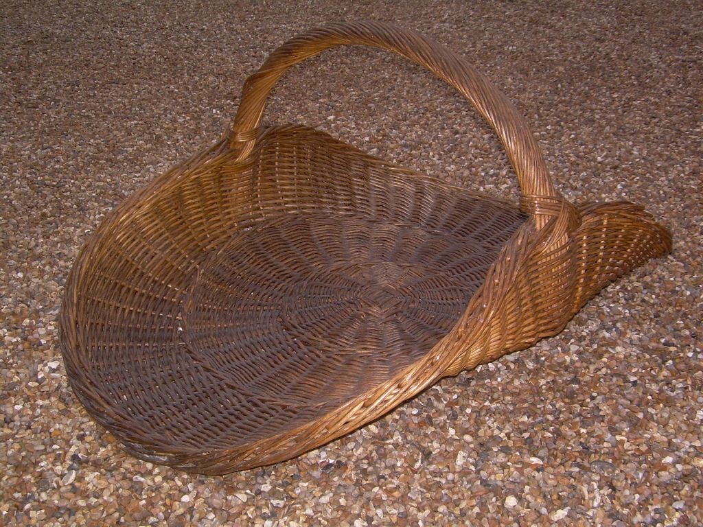 A 19th century English very large size wicker basket with carrying handle, probably originally a flower seller's basket, now suitable next to a fireplace for logs and kindling