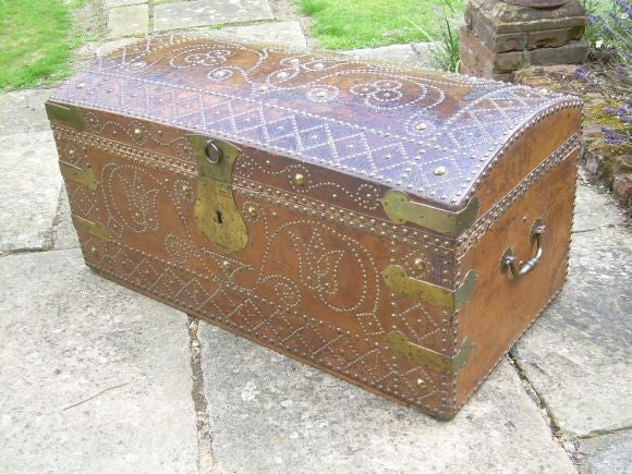 An 18th century highly decorative saddle brown leather trunk having elaborate nailhead decoration with shaped copper corner plates and lockplate.  Original decorative iron carrying handles.