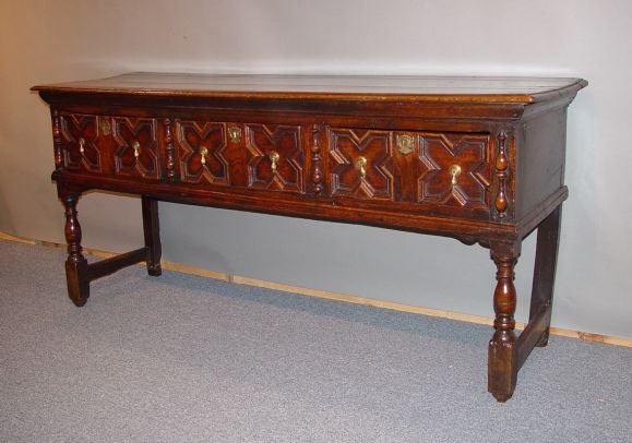 A 17th century English oak low dresser from the reign of Charles II with molded top over three geometric molded drawers on balustrade turned legs joined by stretchers at ends.  Great color and presence.