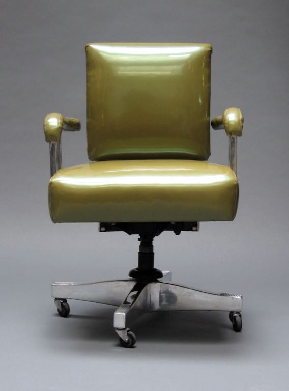 Executive armed desk chair of aluminum featuring rare pre-WW11 base, upholstered in faux patent leather acid green vinyl.