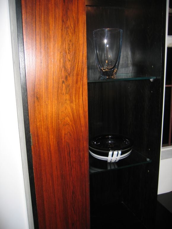 Chic storage units, with open lighted shelves to display your favorite objet. Ebonized oak with rosewood fronted doors. Glass shelves. Priced individually.