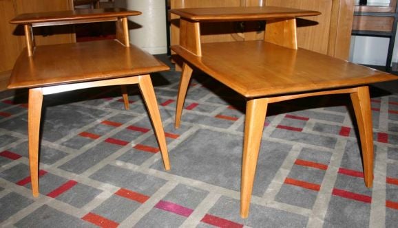 Pair sleek blonde wood two-tier side tables with slightly curved legs.
