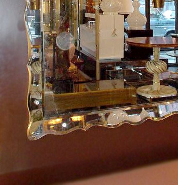 A beautiful oversize mirror with a double bevelled and scalloped edge with silver leaf wood frame.