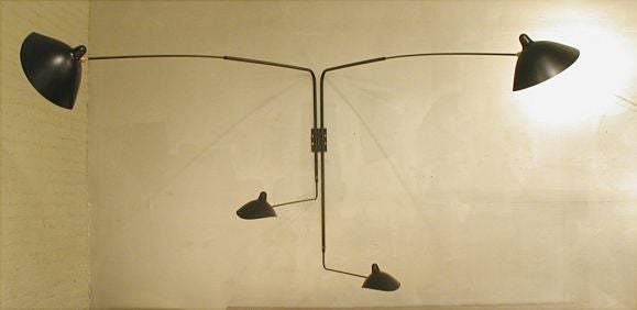 Licensed edition from Serge Mouille's original design, created in 1952.<br />
<br />
This sconce is designed so that one short and one long arm rotate at the same time creating a unique effect with illumination. Shades pivot in place. Switches