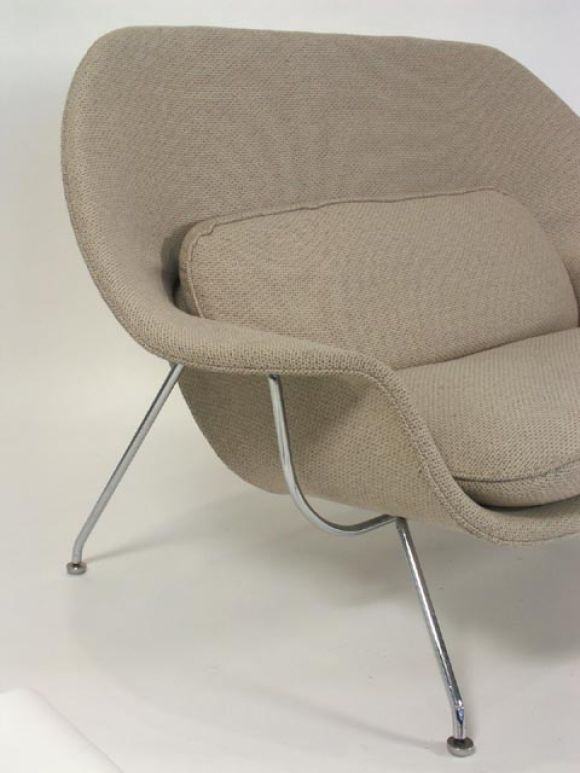 Uncommon mate to Saarinen's well known Womb Chair. Sculpturally curved frame, supported on a chromed base with the original feet. Upholstered in original oatmeal wool, with heavy down filled cushions. A second settee with black frame is available,