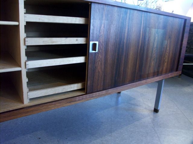 Impressive sideboard in rosewood veneer by Hans Wegner for Ry Mobler. A pair of tambour doors slide effortlessly to conceal a pair of open compartments with adjustable shelves, the center with four shallow flatware drawers. This is the high end