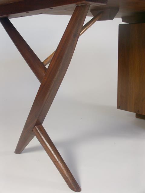 Excellent conoid desk by Nakashima 1970's. Black walnut construction throughout, with free edge desktop, with beautiful natural hole detail. Single three drawer pedestal, and Conoid leg support. The pedestal can be easily rotated to provide left