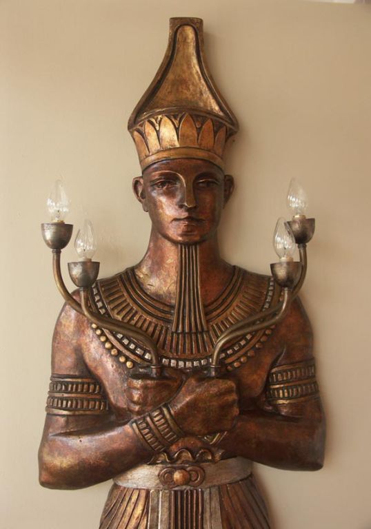 Incredibly unusual wall sconce in the form of a huge Egyptian pharoah. Towering over seven feet tall, the plaster relief pharoah stands solemnly in traditional dress with arms crossed. The surface has been gilt in a variety of metal leaf, including