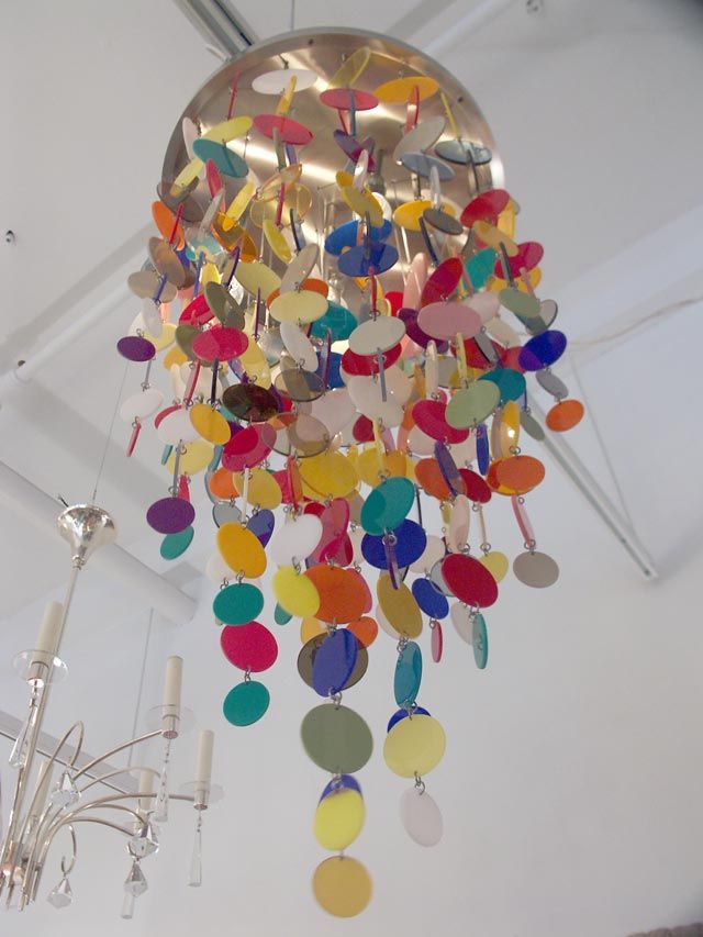 Reminiscent of the restrained shell chandeliers by Verner Panton, this Italian creation throws restraint out the window. Dozens of strands of colored acrylic discs of various sizes are hung from chains, concealing the internal light sources. A true