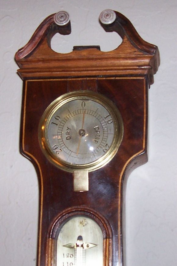 The banjo shaped line inlaid case inset with a hydrometer, thermometer, bull’s-eye mirror within a reeded frame, large diameter silvered barometer dial and spirit level inscribed: P. Boffi, Hastings, surmounted by a scrolled broken arch pediment