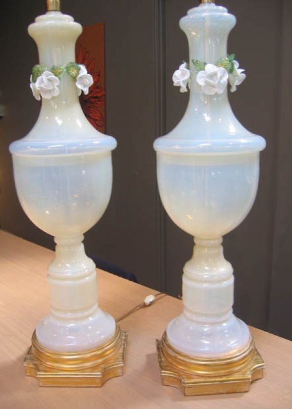 Pair of monumental murano milk-glass urn lamps with gold flecks on gilded wood bases.  Solid brass pine-cone finials.  Decorative white glass roses adorn top of lamp.  Marked with original tags 'Marbro.'