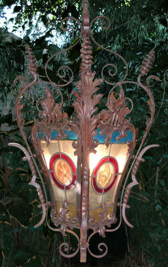 Beautiful wrought iron lamp with skillfully hand painted images of two flowers, a swallow and an egret (or crane), one painted on each of the four sides. The side with the egret is hinged and opens like a door by turning a small knob. This lamp was