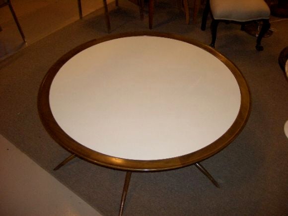Large round white glass table framed in walnut with collapsible spider leg base. The legs on the table have brass sabots and brass hinges.  The glass is original and virtually free of scratches.