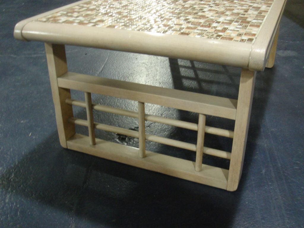 A coffee table with an interesting base of wood lattice. Top inset with a tile mosaic and the top is groved at the side and rounded at the ends.