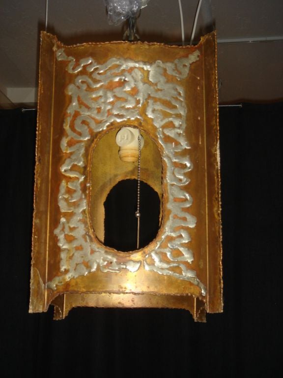 An unusual metal lantern with an applied lighter metal element for decoration in a traditional Chinese hanging lantern form. The serrated edges of the metal reminiscent of Paul Evan's work.