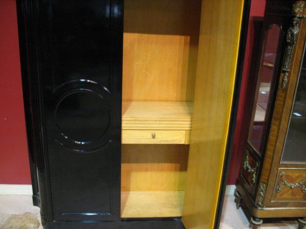 Fine ebonized tall cabinet or cupboard in a restrained neoclassical form fronted by two hinged doors with single key lock. The top a solid marble slab with gilt bronze border. 

Finished interiors with adjustable shelves the center shelf with two