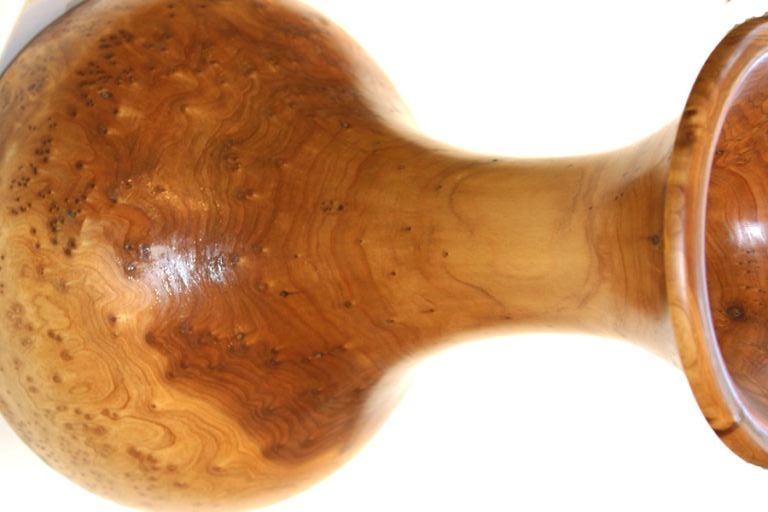 The everted lip of this vase form with globular base and raised on a pad foot is turned and hollowed out of a single piece of Maple burl.  Not water proof.  Liner can be fabricated.