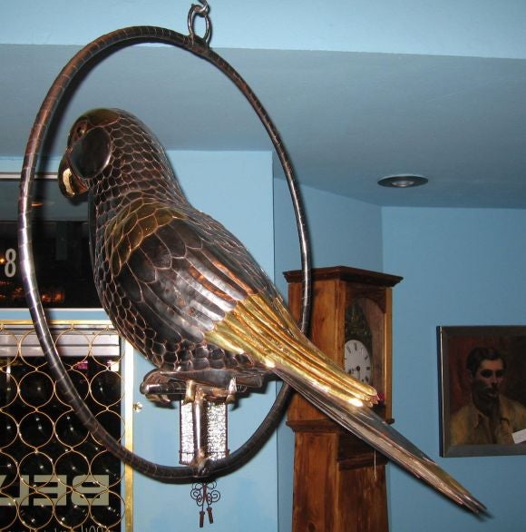 Fantastic and beautifully made hanging parrot sculpture dating to the late 1970's. Made of hundreds of fingernail sized pieces of chromed steel, there are accents of copper and brass as well.  Eyes are some sort of black glass or possibly jet.  In
