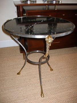 This round marble, steel and brass end table is classical in style with brass rams heads and feet. The black marble top adds elegance and charm. It is in the style of Maison Jansen.
The marble has not been polished for a long time, nor will be.