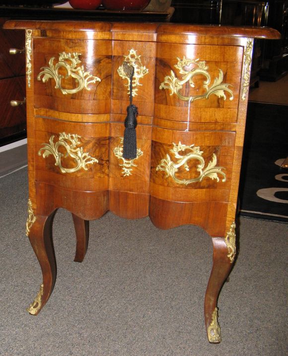 An antique mahogany commode featuring two drawers, a serpentine shaped front, a shaped top with cross banding, cabriolet legs and ormolu decorations and drawer pulls, German, circa 1840.
