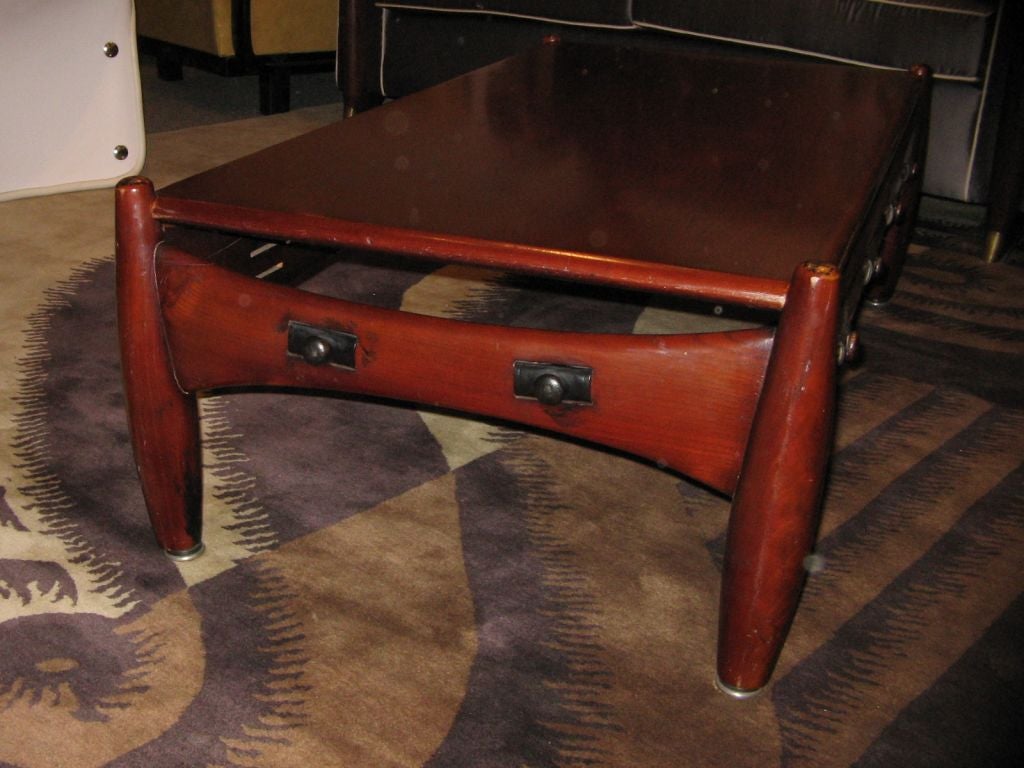 A coffee or cocktail table, model Sheriff featuring a rectangular body in mahogany with legs that taper at both their tops and bottoms, a shaped table skirt with applied decorations and an original ISA sheriff label to the underside. By Sergio