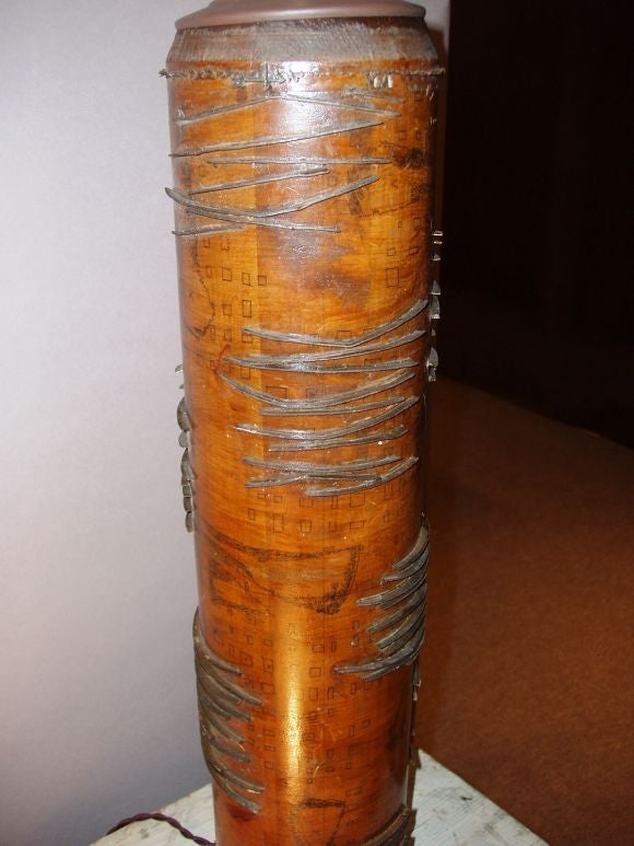 Un rouleau de papier peint marron transformé en un magnifique pied de lampe.<br />
Des éléments de design en métal entourent la base en bois.