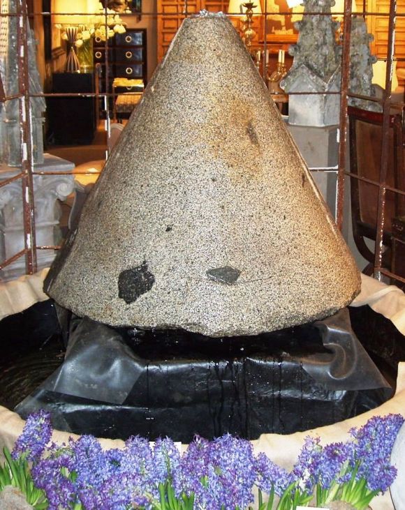 Granite olive press now used as a fountain. The water gently cascades over the sides in a very zen like fashion. The water height coming out of the fountain can be adjusted via the pump.<br />
A suggestion is to have the fountain base surrounded by