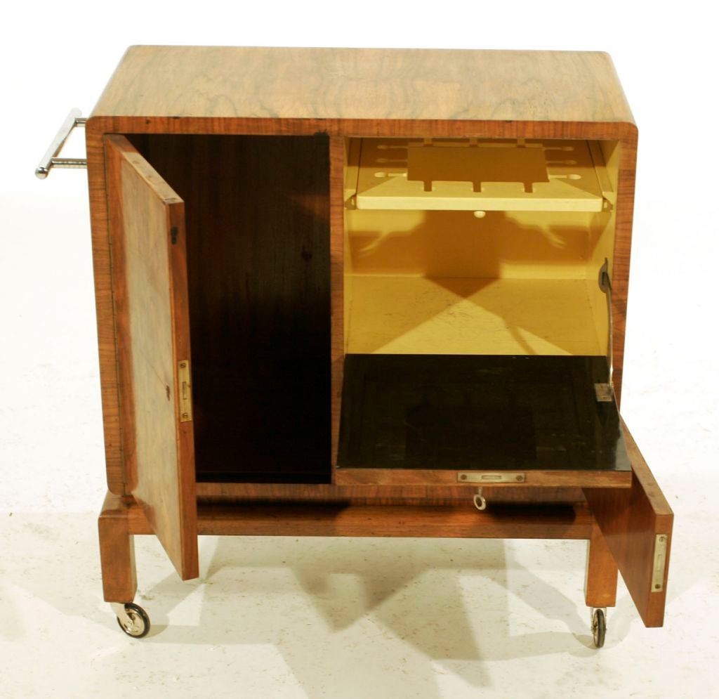 intended for bar service: book-matched burled walnut with nickel handle and chrome/rubber wheels; three compartments, one with slide-in/slide-out cordial glass rack and black lacquer on interior side of door