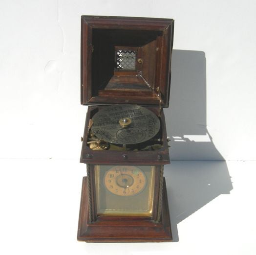 This is a real charmer! The petite wind up clock case also houses a musical disc player in the top. At the turn of the hour, the mechanism is activated, and the perforated metal disc plays a tune. The clock has been serviced, and works well. There