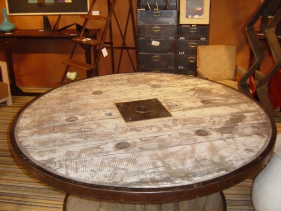 Industrial spool round table with iron banding, and old painted top. Seats 8-10.
