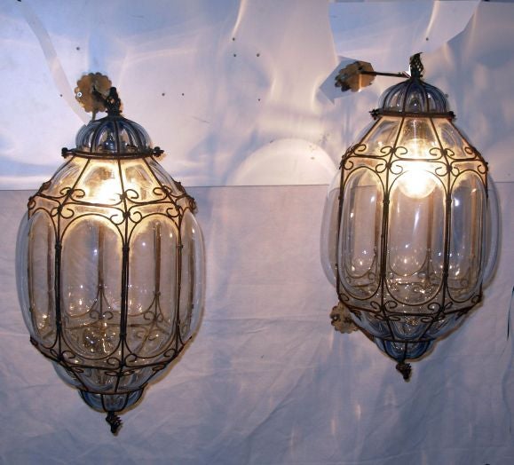 The wonderful light blue color gives grace and elegance to this unusual pair of Venetian lanterns Two arms connect each lantern to the wall. There is rust on the wrought iron and traces of the original gilding on the plaques to attach the fixtures