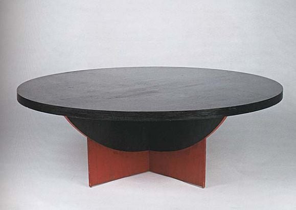 Geometric low table in painted wood. Round top mounted on a solid X-shaped base. <br />
Dimensions: 47 in. diameter x 16 in. high