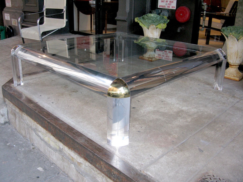 One coffee table design by  Karl Springer with half round clear lucite frame, with brass corner accent and glass top.