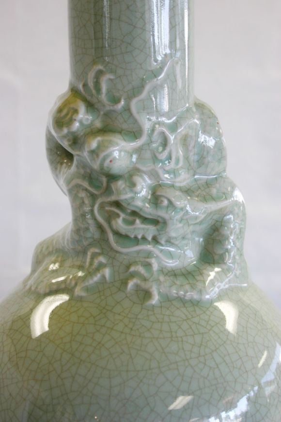 Pair Chinese style porcelain lamps with dragons in celadon crackle glaze. Ebonized wood base. Brass hardware