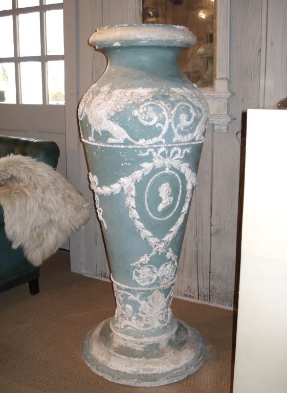 A monumental plaster urn/vase painted in 'wedgewood green' and white with an all over relief design.