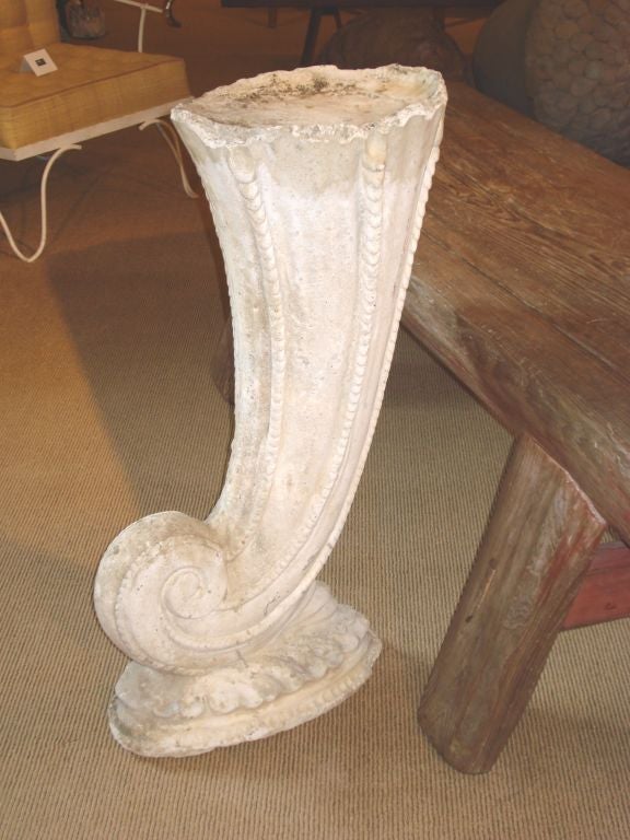 A cast concrete elongated shell, forming a pedestal as it rests on a 