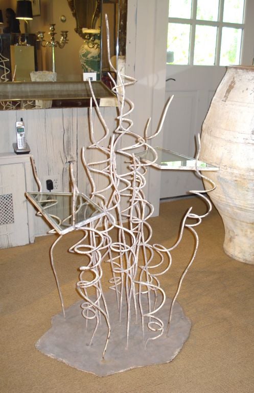 An unusual piece that is part sculpture, part drinks table or plant stand; about 20 iron sprirals erupt skyward with two trapezoidal glass topped 'tables', one on each side