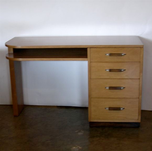 This small desk is a medium tone birch with contrasting wood and aluminum hardware. It has a nice working surface with ample leg room.