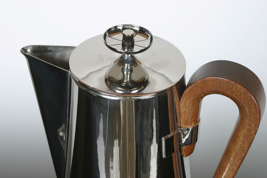 A coffee or tea serving set designed by Tommi Parzinger for Dorlyn Silversmiths. This set is made of heavy brass, and has been newly plated in a nickel finish. It consists of a pitcher with wood handle, equipped with a burner and snuffer, creamer,