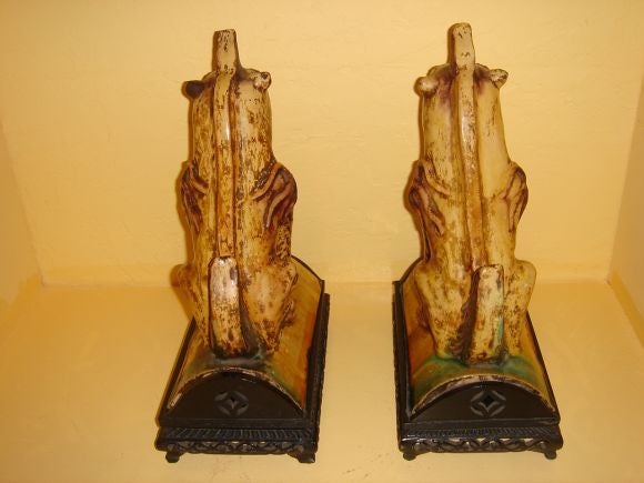 A pair of Chinese foo dog roof tiles on hand carved ebony wooden stands