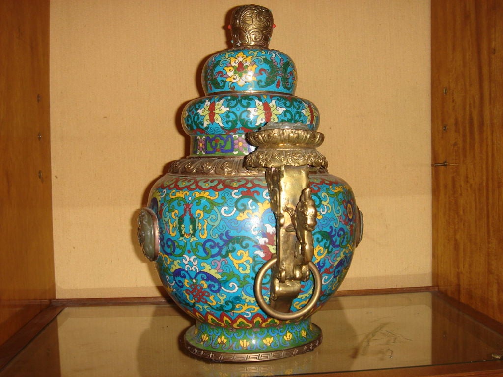 The Censor Vase/Incense Pot is cloisonne' w/ carved dragon design on jade embellishments (front, back, and top of each handle), semi-precious stones (turquiose, coral and jade) lid to the top, metal dragon design to the handles, with gold ring