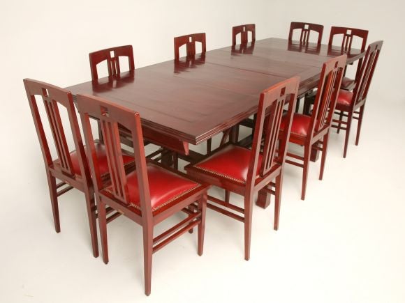 An Aesthetic Movement red mahogany dining table and chair suite, complete with matching hutch and sideboard. The richly figured tabletop, which expands with three 17-inch leaves, rests above an H-form stretcher. A carved and pierced elliptical